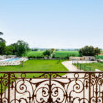 Vue depuis une terrasse en fer forgé sur un parc arboré et une piscine, dans une propriété d’exception en Drôme provençale