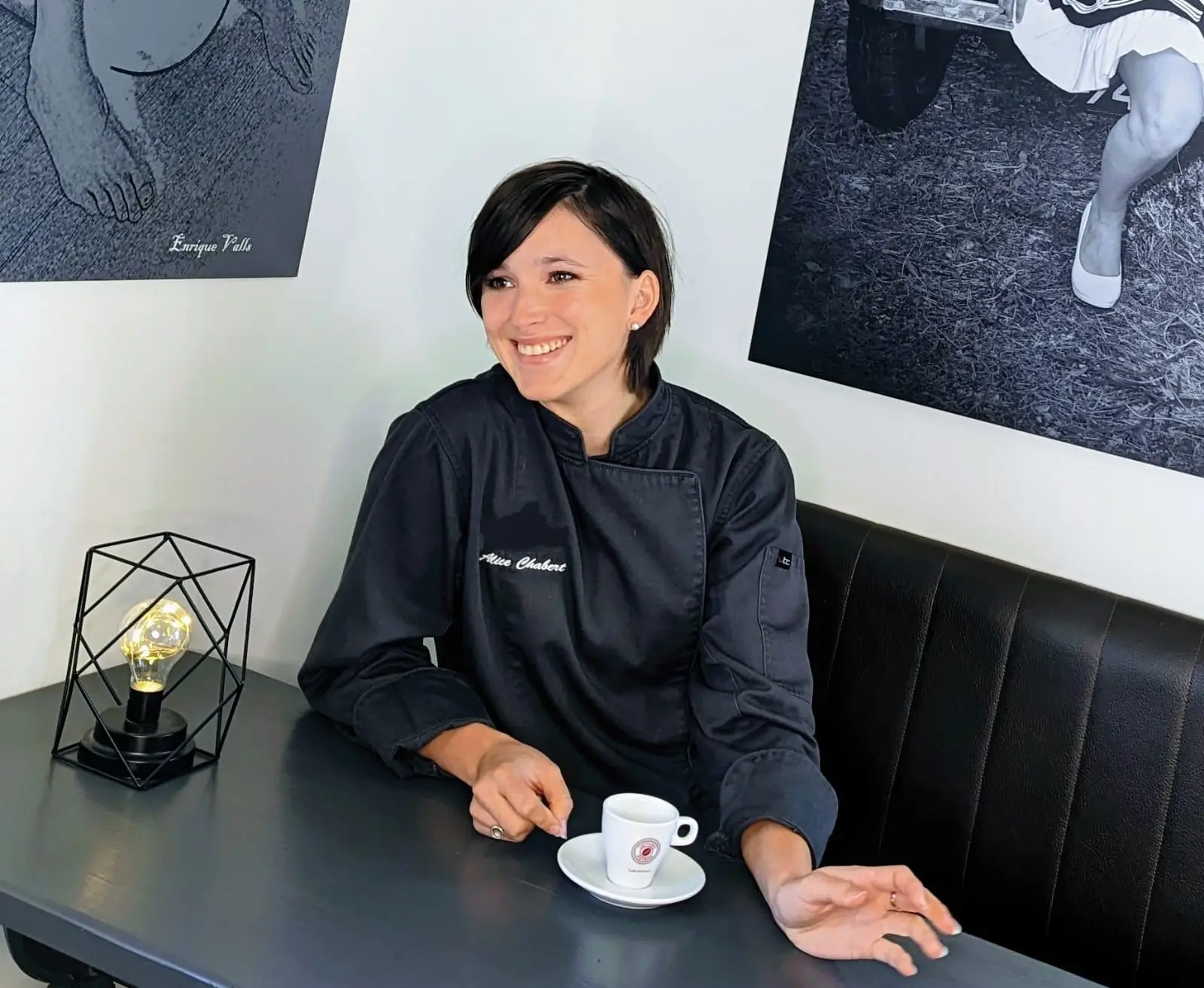 Portrait de la cheffe Alice Chabert en tenue professionnelle, assise avec un café